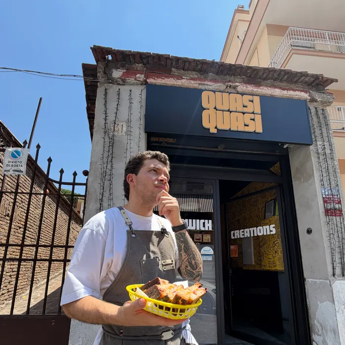 La facciata di Quasi Quasi in Via della Pisana 33, con lo chef davanti e un cestino di panini