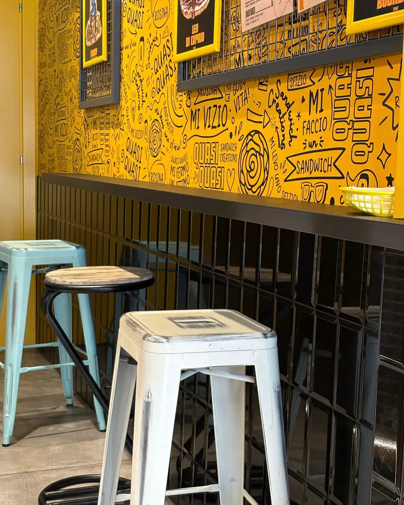 Il locale: il muro giallo disegnato e gli sgabelli